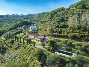Eine Villa am Hang mit Swimmingpool, umgeben von üppiger Vegetation und blauem Himmel.