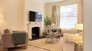 Una sala de estar con chimenea, sofá, sillón y televisión.