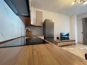 Eine moderne Küche mit Marmorarbeitsplatte, Edelstahlgeräten und einem Essbereich aus Holz.
