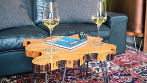A living room with a blue sofa, two wine glasses on a wooden coffee table, and a patterned rug. - 1BR unit near Greyfriars Church with garden views (Edinburgh)
