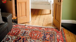 A room with a bed, a wooden door, a hanging coat rack, and a patterned rug. - 1BR unit near Greyfriars Church with garden views (Edinburgh)