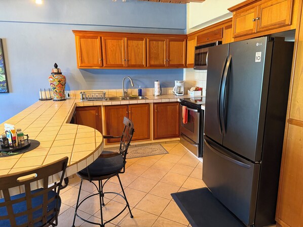 A kitchen with wooden cabinets, a black refrigerator, a coffee maker, and a vase.