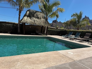 A swimming pool with lounge chairs, a thatched-roof structure, and palm trees. - Villa Bahia 4C  Condo with fabulous views in San Carlos, Mexico (San Carlos)