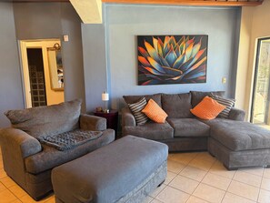 A living room with a gray sectional sofa, a matching ottoman, and a floor lamp. A colorful abstract painting is on the wall. - Villa Bahia 4C  Condo with fabulous views in San Carlos, Mexico (San Carlos)