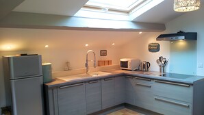 A modern kitchen with a skylight, a refrigerator, a toaster, and a coffee maker.