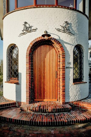 A building with a large wooden door, arched windows, and a brick exterior. - Architectural gem with sea view (Norderney)