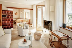 A modern living room with a sofa, coffee table, TV, and a dining area with a table and chairs. - Architectural gem with sea view (Norderney)