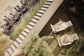 A top-down view of outdoor seating with tables and chairs, surrounded by a concrete border and greenery. - Architectural gem with sea view (Norderney)