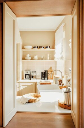 A narrow kitchen with white cabinets, a coffee machine, a sink, and a tea kettle. - Architectural gem with sea view (Norderney)