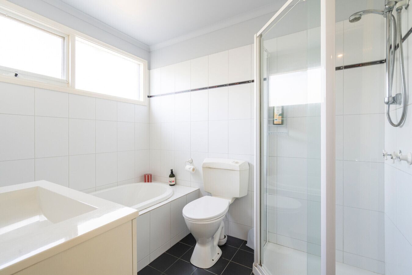 A bathroom with a bathtub, toilet, and glass shower enclosure.