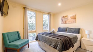 Une chambre à coucher avec un lit, une chaise, une table de chevet et une fenêtre.