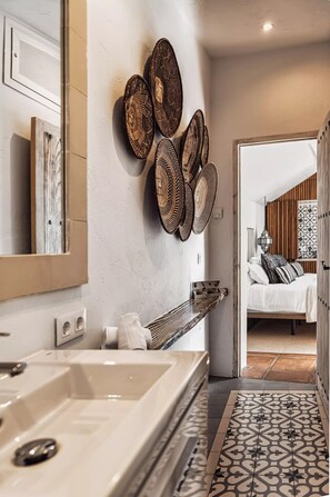A modern bathroom with a large mirror, a white bathtub, and a decorative wall with woven baskets. - Bohemian villa with pool near Canillas (Canillas de Aceituno)