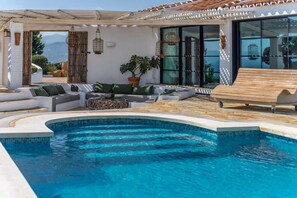 A poolside area with a curved pool, outdoor seating, and a view of the mountains. - Bohemian villa with pool near Canillas (Canillas de Aceituno)