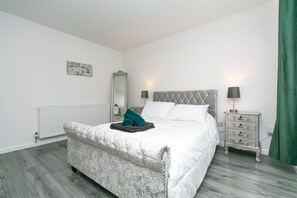 Un dormitorio con cama, cómoda, espejo y radiador.