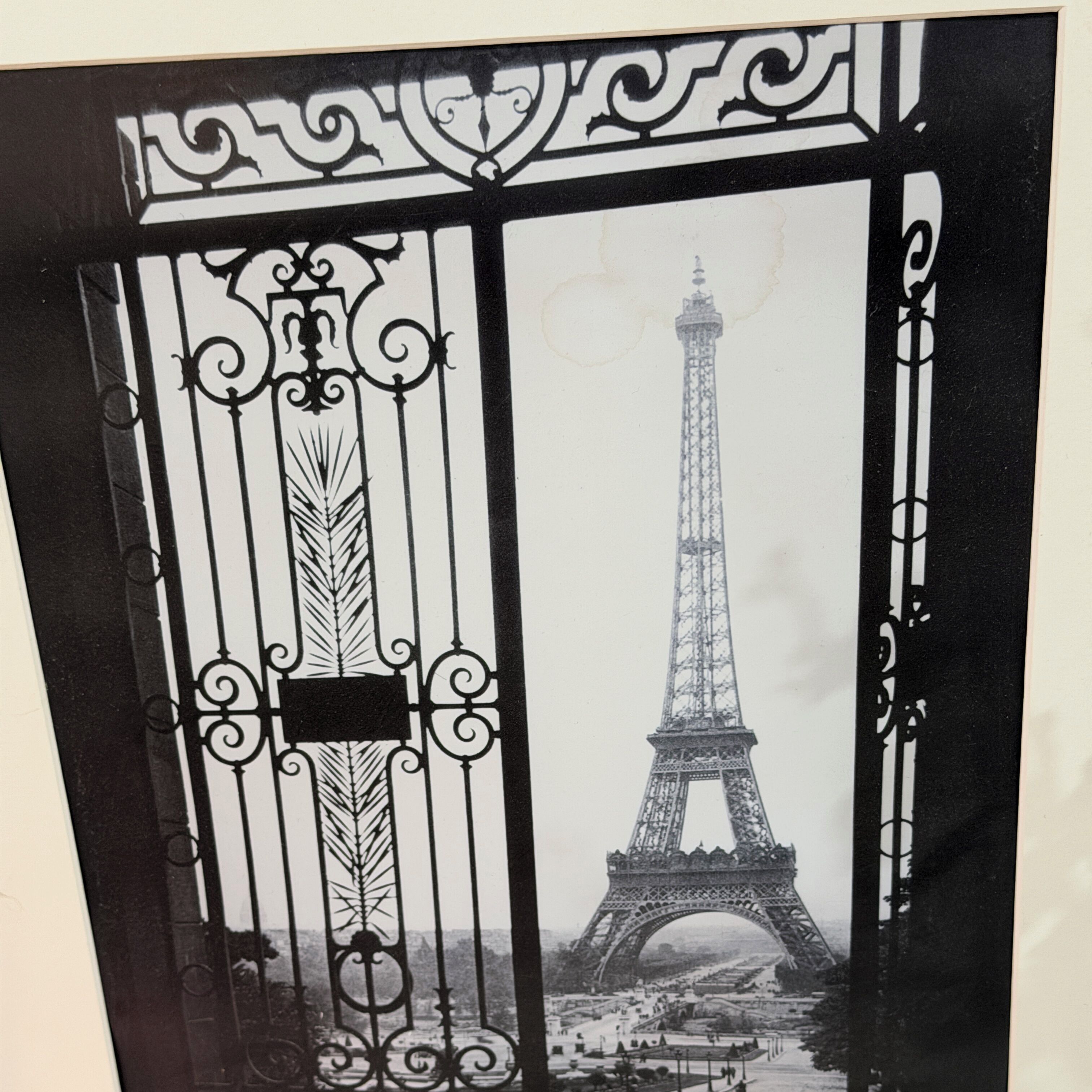 A black and white photo of the Eiffel Tower through a decorative iron gate.