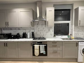 Een moderne keuken met een inbouwoven, magnetron, koffiezetapparaat en een gasfornuis.