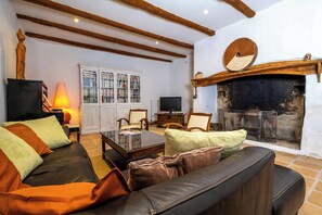 Ein Wohnzimmer mit Kamin, einer Ledersofa und einer Vitrine.