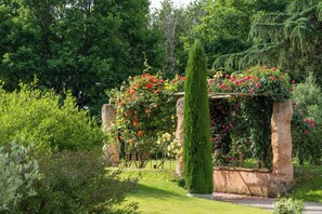 Ein Garten mit einer Steinstruktur, üppigem Grün und blühenden Pflanzen.
