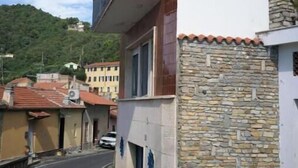 A narrow street with a building featuring a stone wall and a balcony. - Hostdomus - Brezza Marina House (Moglio)
