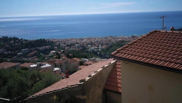 Un paisaje urbano costero con vista al mar, edificios de tejas terracota y cielo despejado.