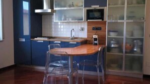 A modern kitchen with blue cabinets, a wooden countertop, and a glass-fronted cabinet. - Hostdomus - Brezza Marina House (Moglio)