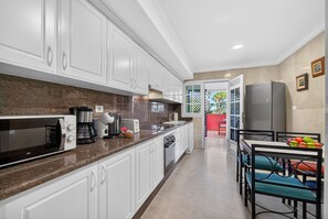 A kitchen with white cabinets, a microwave, a coffee maker, and a refrigerator. - Duque Dream Villa Suites (Costa Adeje)