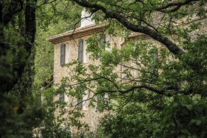 Ein Gebäude aus Stein mit vielen Fenstern, umgeben von üppiger Vegetation.