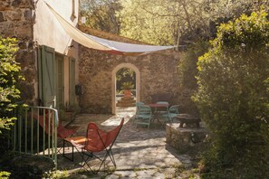 Eine Terrasse im Freien mit Steinboden, einem Tisch und Stühlen sowie einem schattigen Bereich.