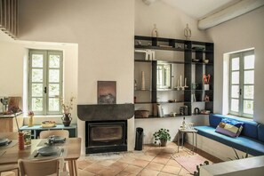 Ein Wohnzimmer mit Kamin, Essbereich, Bücherregal und einem Fenster mit Aussicht.