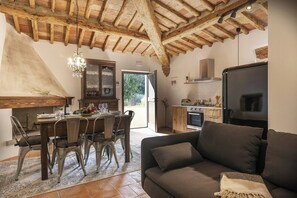 Ein rustikales Interieur mit Essbereich, Holzbalkendecke, einer Couch und einer Küche mit Herd.