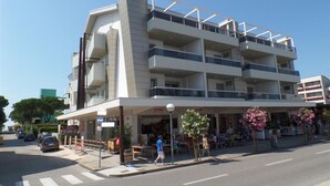 Um hotel com vários andares, varandas, um café no térreo e área de estar ao ar livre.