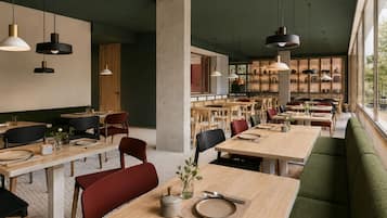 Un restaurant spacieux avec de hauts plafonds, des luminaires suspendus et une vue dégagée grâce à de grandes fenêtres.