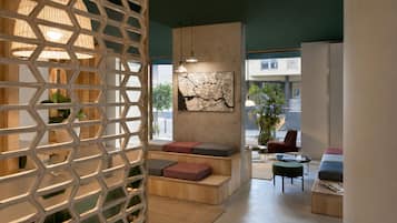 Un salon moderne doté d’une cloison aux motifs géométriques, d’un grand tableau abstrait et offrant une vue sur l’extérieur.