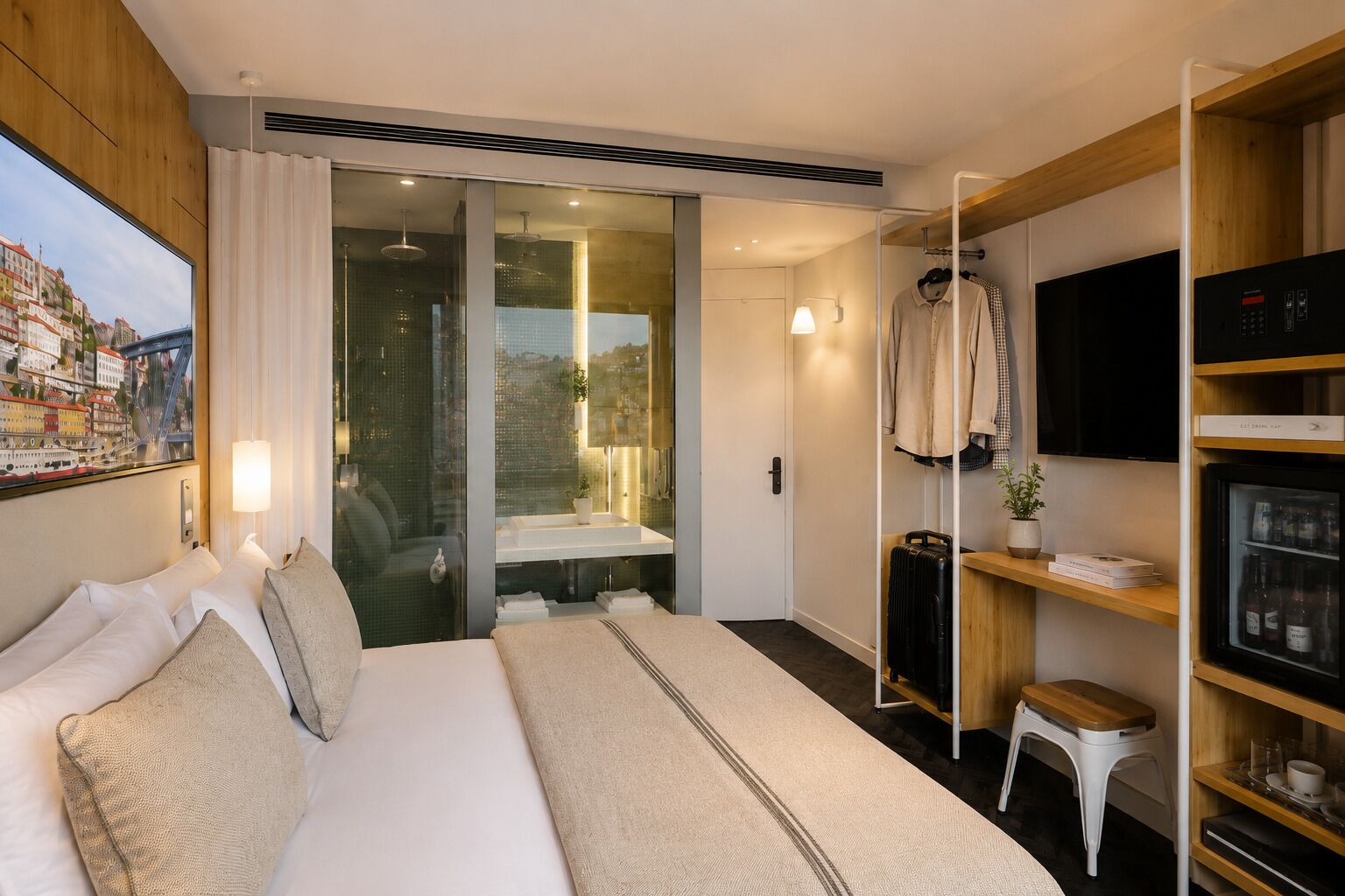 Quarto de hotel com cama, televisão, minibar e vista para a paisagem urbana.