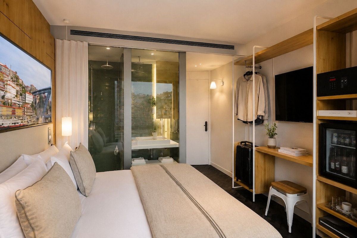 Une chambre d’hôtel équipée d’un lit, d’une télévision, d’un mini-bar et offrant une vue sur le paysage urbain.
