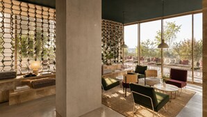 A modern interior with a concrete column, hexagonal wall panels, and a seating area with tables and chairs. - Hotel Gat Massarelos 3  (Porto)