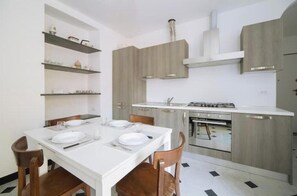 Een moderne keuken met witte kastjes, een gasfornuis en een eettafel gedekt voor vier personen.