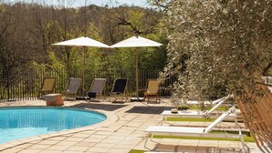 A pool area with lounge chairs, umbrellas, and a fenced garden. - Designer cabin with shared pool in Bras (Bras)