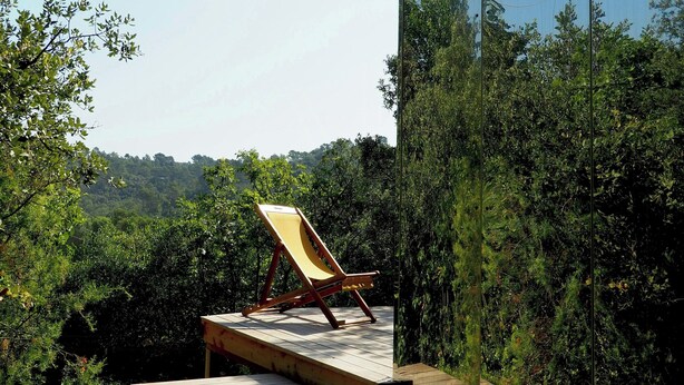 A wooden deck with a single lounge chair, surrounded by dense greenery and a clear sky. - Designer cabin with shared pool in Bras (Bras)
