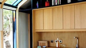 A modern kitchen with wooden cabinets, a sink, and a dining area with a chair. - Designer cabin with shared pool in Bras (Bras)