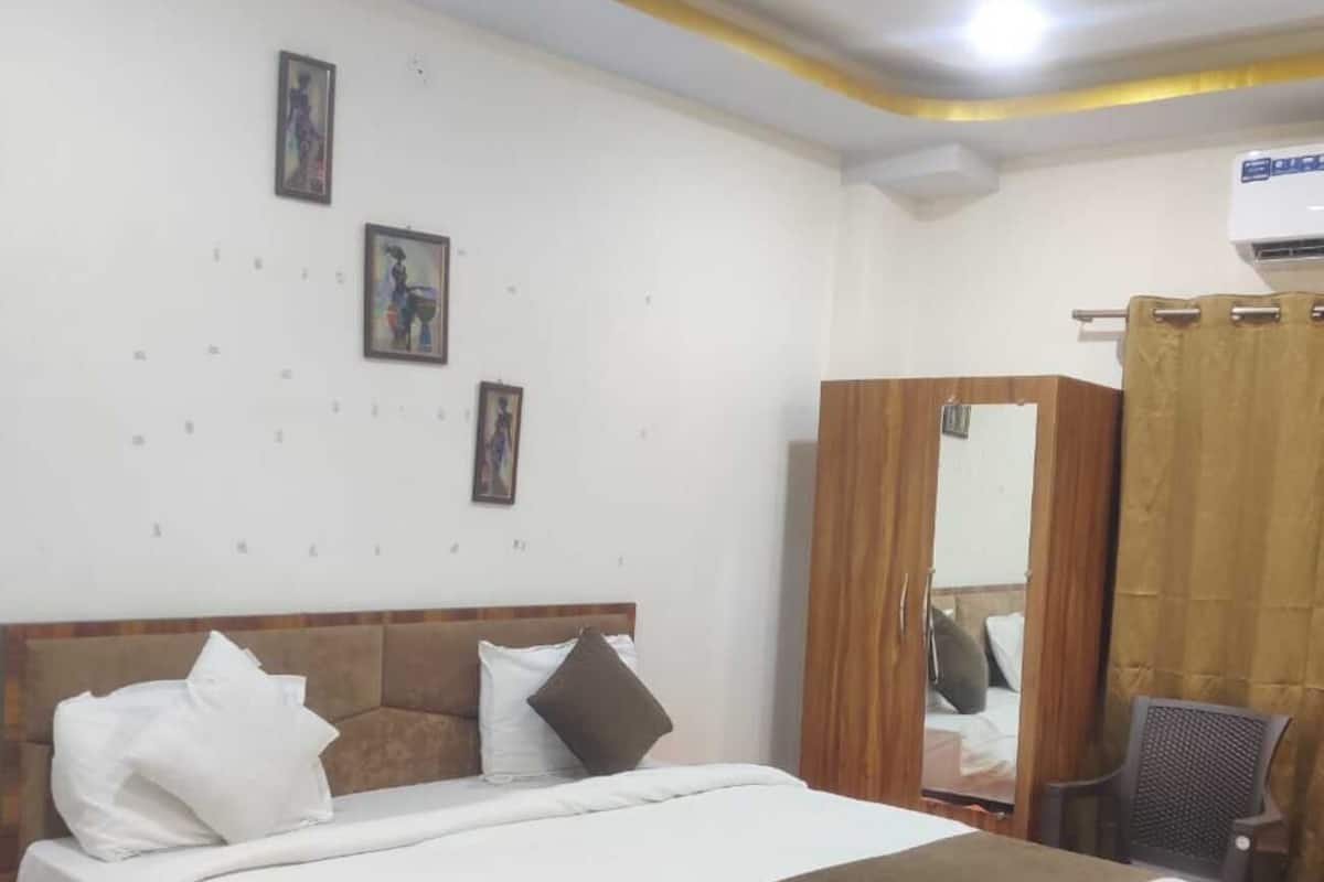 Una habitación de hotel con una cama de madera, ropa de cama blanca, un espejo, una silla y un ventilador de techo.