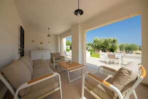 Ein geräumiges Zimmer mit Sofa, Sesseln, einem Tisch und Blick ins Freie.