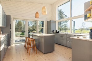 Una cucina moderna con ampie finestre, un'isola centrale e sgabelli di legno.
