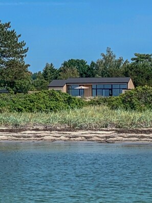 A modern house with a flat roof, large windows, and a view of the water. - Architect-designed house by the sea (Knebel)