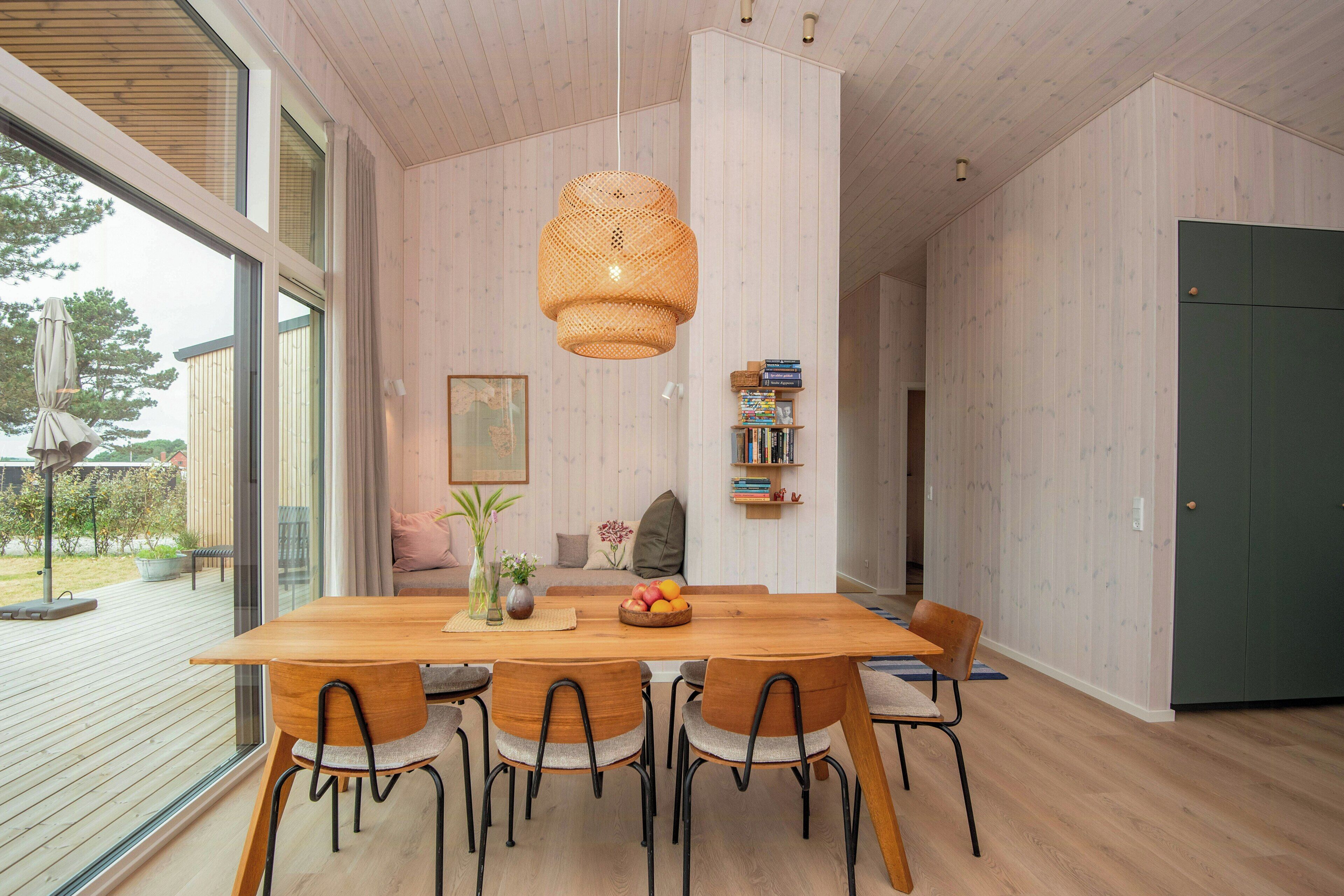 Un espace repas moderne avec une table en bois, des chaises et un luminaire suspendu.