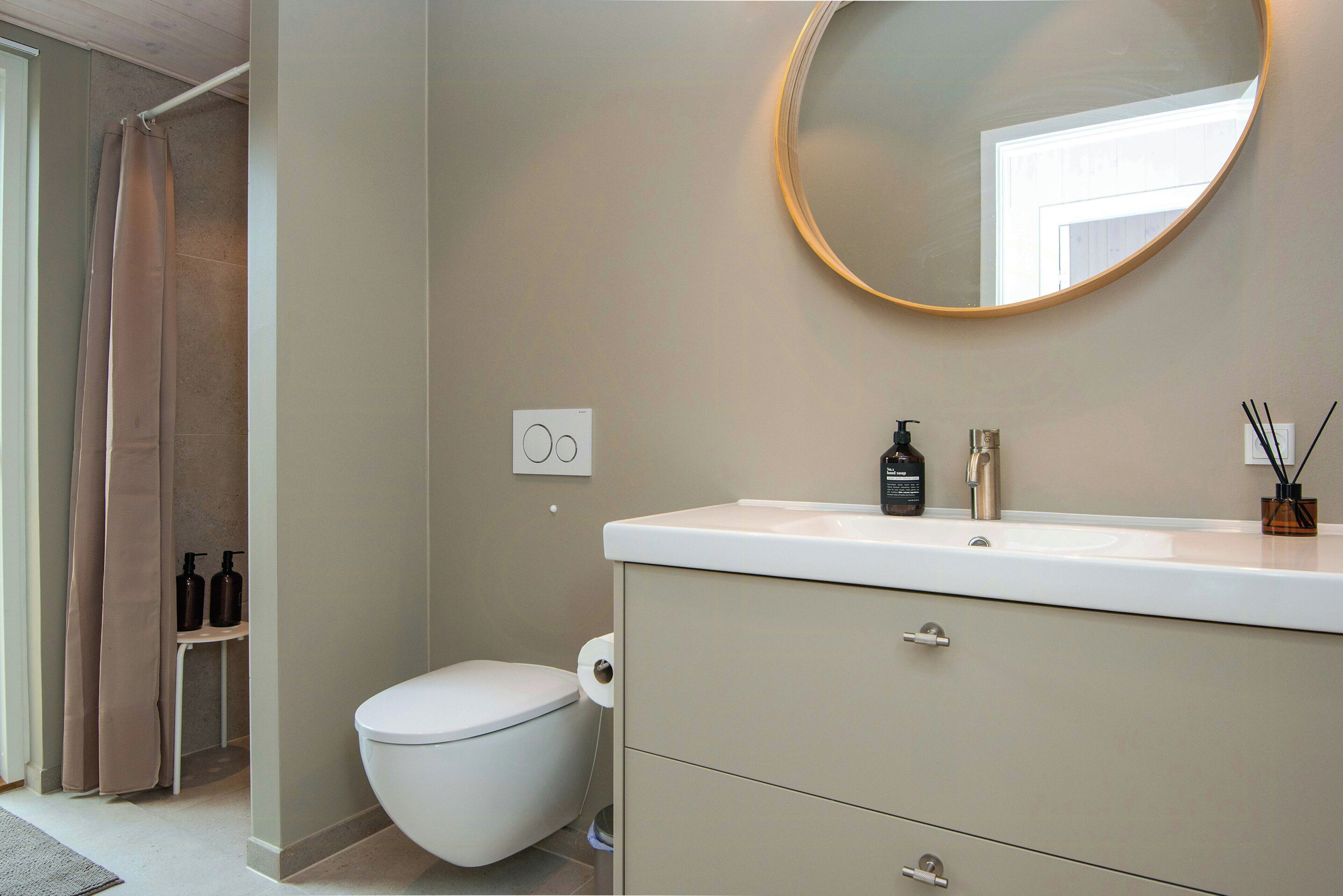A bathroom with a toilet, a sink with a mirror, and a shower curtain.