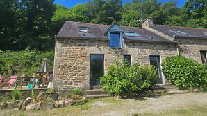 A stone building with a sloped roof, a small window, and a door. - Cottage in wooded heart of Brittany (Ploërdut)