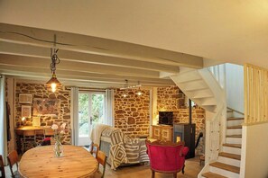Ein gemütliches Interieur mit einer Steinwand, einem Holztisch, einem roten Stuhl und einer Treppe.
