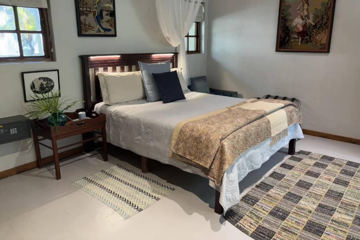 Un dormitorio con cama, mesitas de noche, cortinas en la ventana y decoración en la pared.