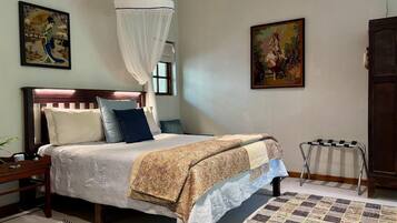 Une chambre à coucher bien rangée, avec un lit, une table de chevet et une petite table d’appoint.